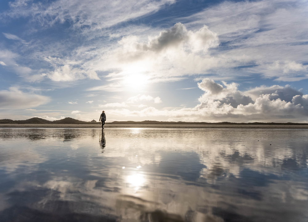 person walking near ocean at sunset