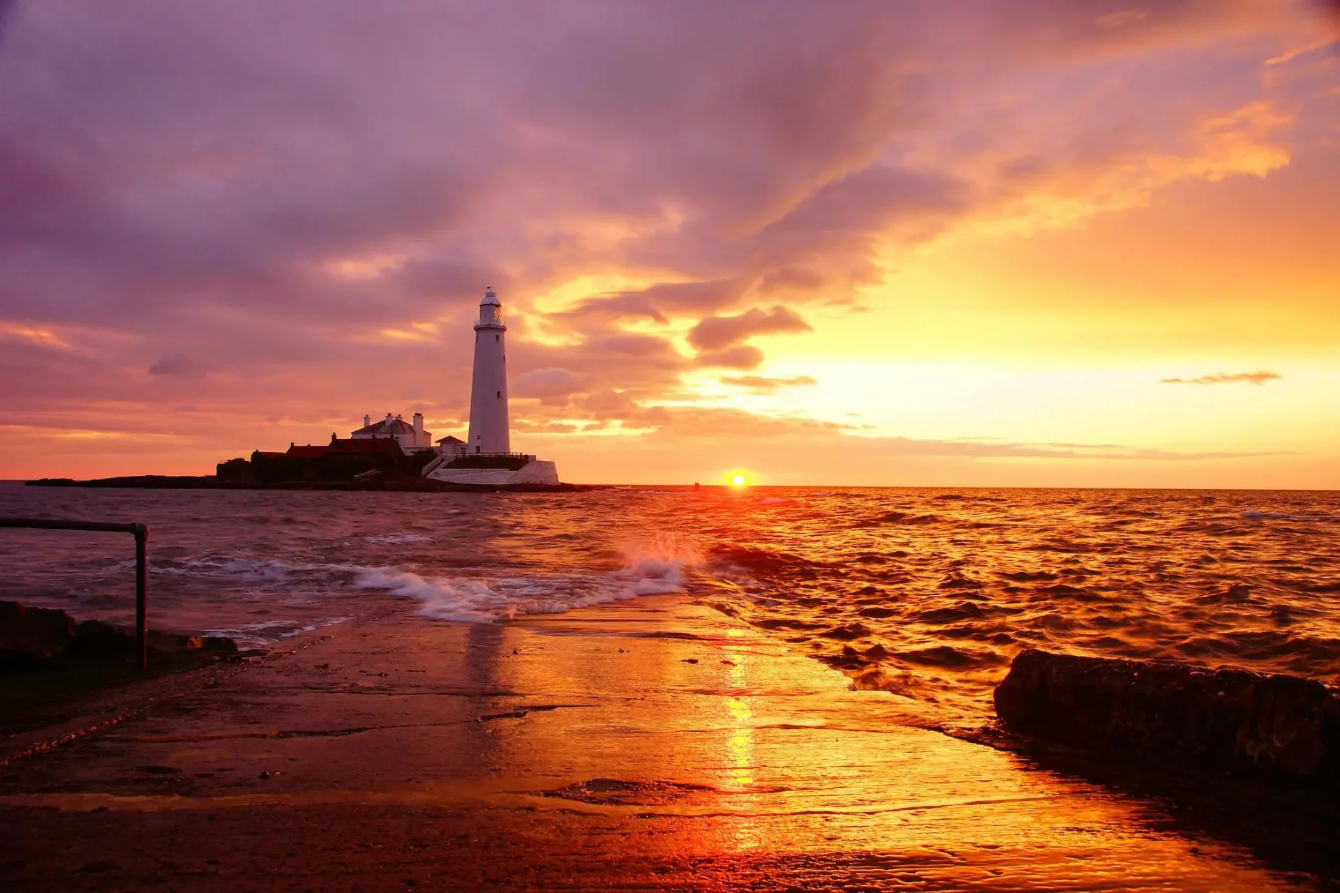 a lighthouse on a beach at sunset